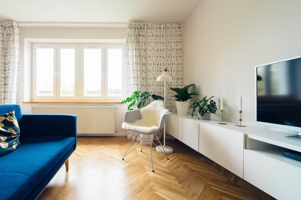 A bright airy living room with a blue sofa and herringbone hardwood floor